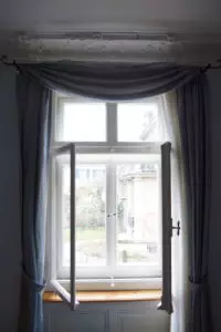 Kastenfenster mit Stuck und Gardinen